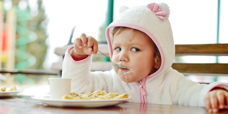 una bambina con una felpa da orsetto mangia la colazione