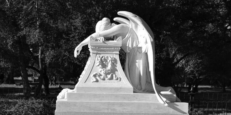 una scultura tombale con un angelo che piange