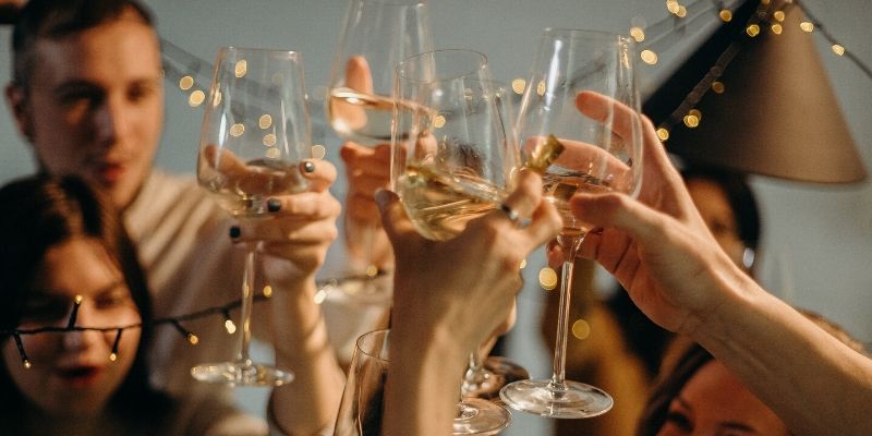 un gruppo di persona brinda con dei calici di vino bianco