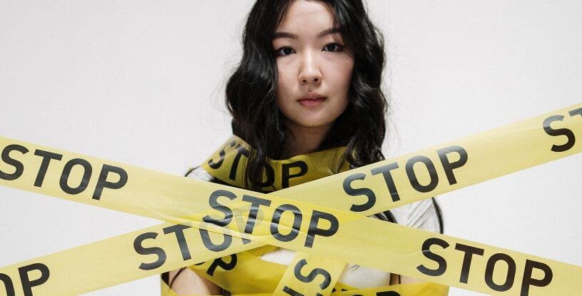 una ragazza orientale con del nastro adesivo intorno che dice STOP