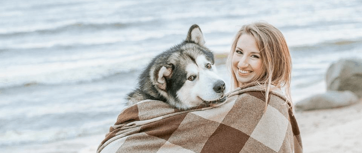 una ragazza sulla spiaggia col suo cane husky
